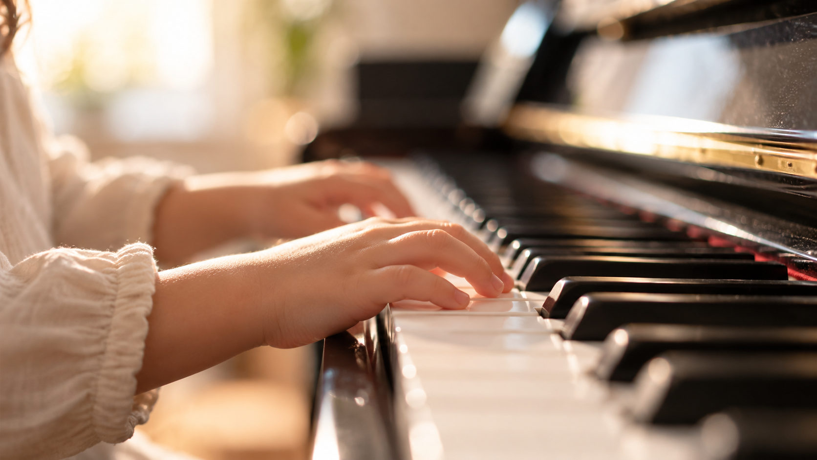 Mani di un bambino sulla tastiera del pianoforte